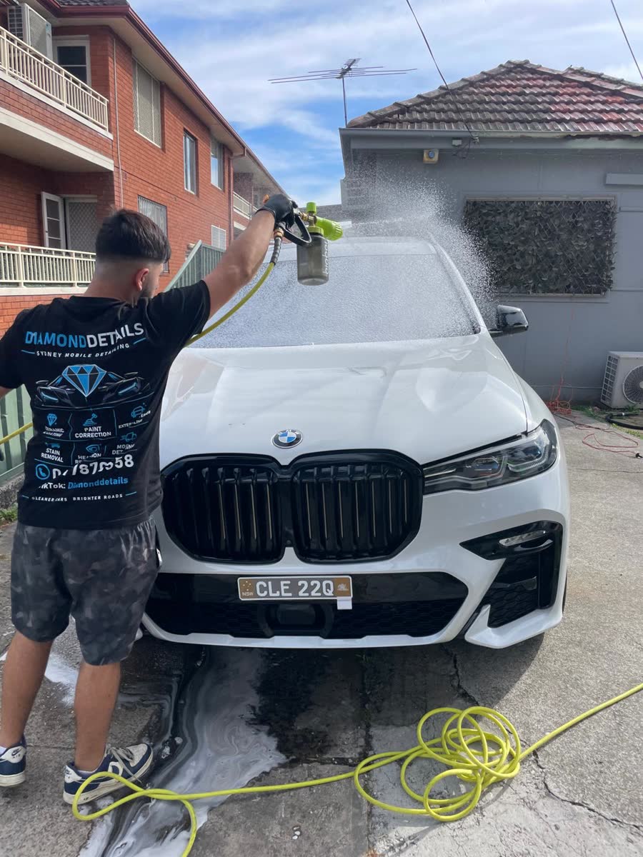 Detailer rinsing a white BMW X7